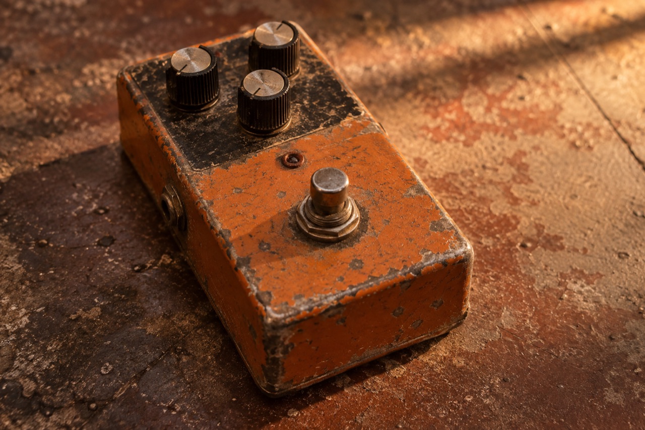 Illustrative close-up of a scuffed analog guitar pedal